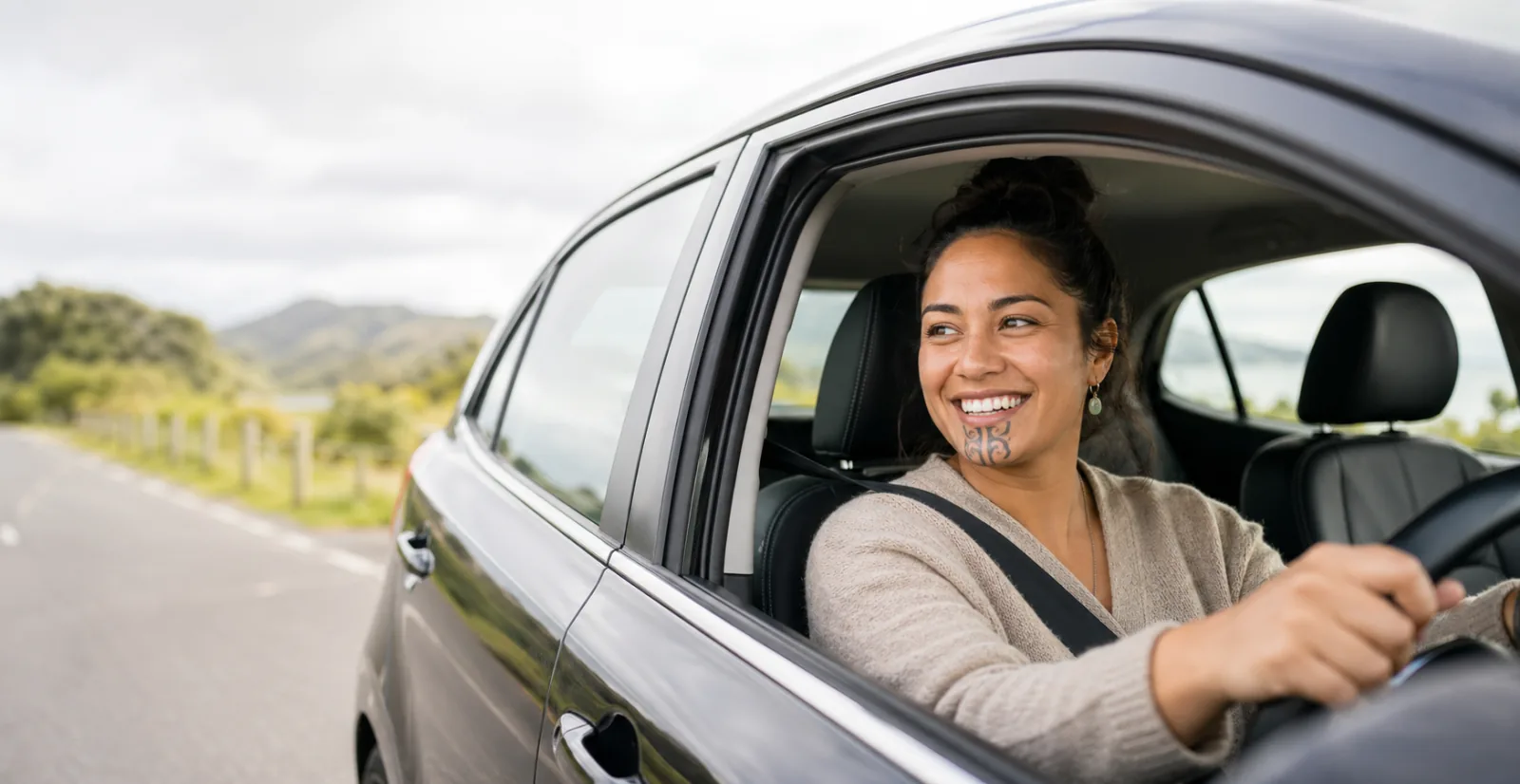 Smiling Māori woman seen through a car window